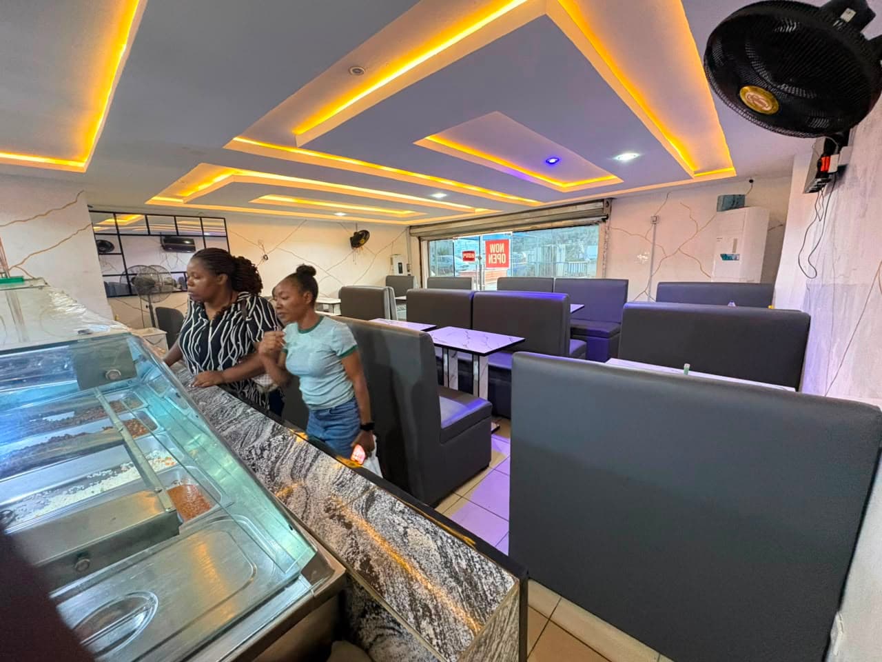 Guests choosing plates at the glass food display counter inside the dining room